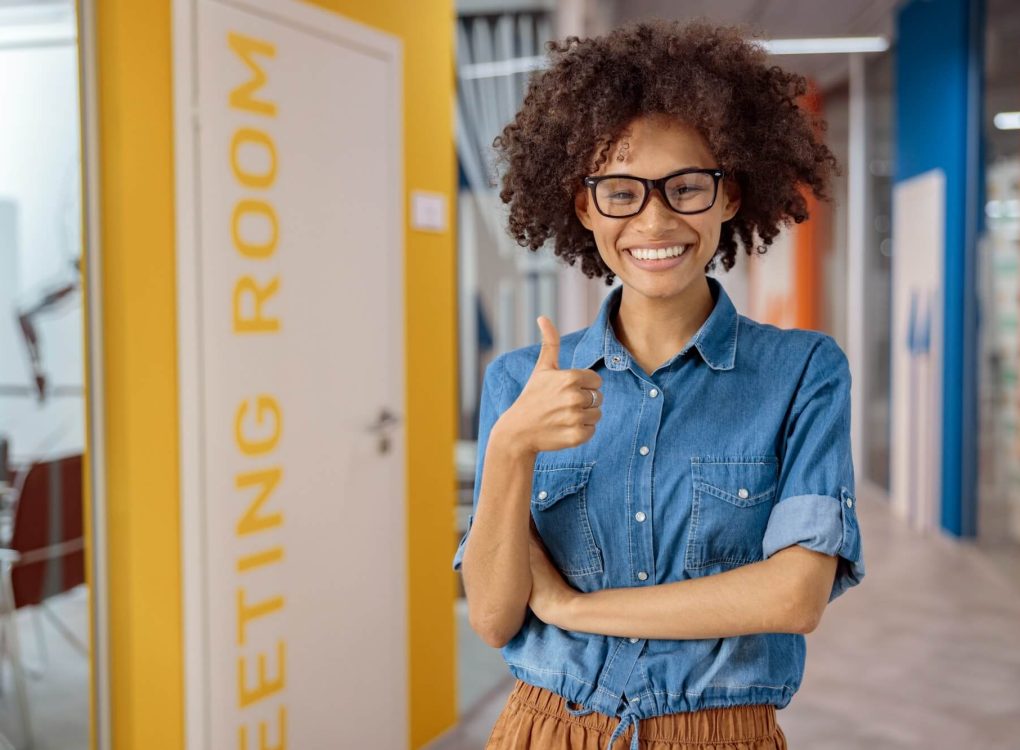 multiethnic-young-lady-holding-thumb-up-in-coworking